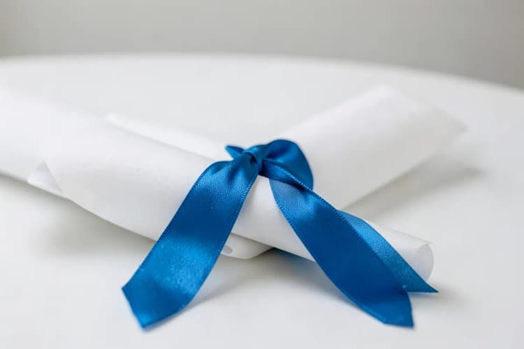 Diploma de graduação em um fundo branco com uma fita azul