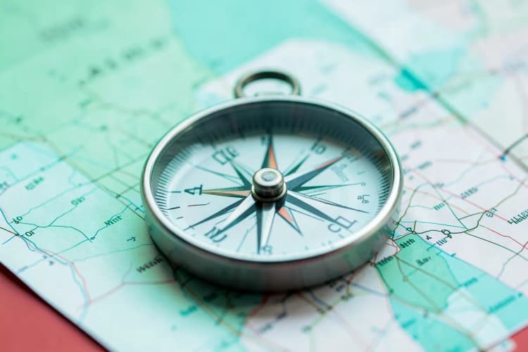 Uma bússola apontando para o norte sobre um mapa desdobrado, representando orientação e direção em processos de certificação