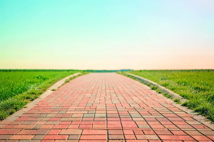 Um caminho de tijolos que leva a um horizonte claro e ensolarado, simbolizando o próximo passo e um futuro promissor