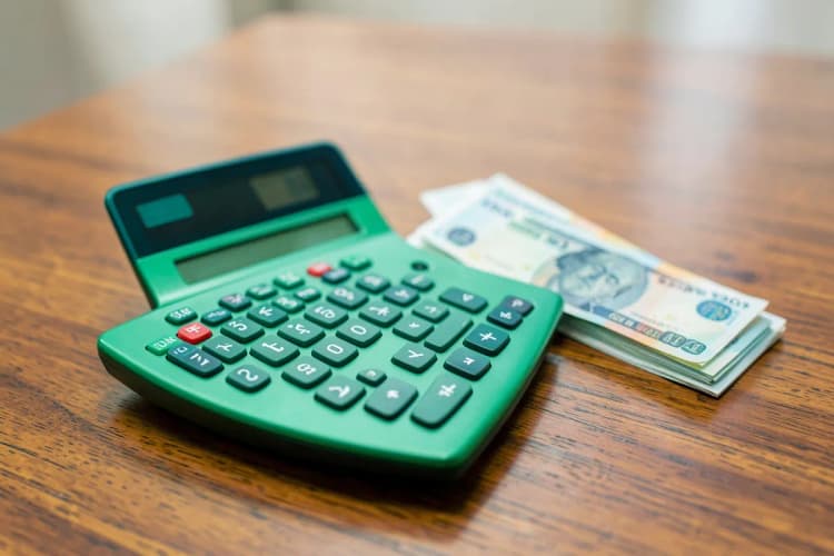 Uma calculadora e notas de dinheiro sobre uma mesa, representando o custo da certificação.
