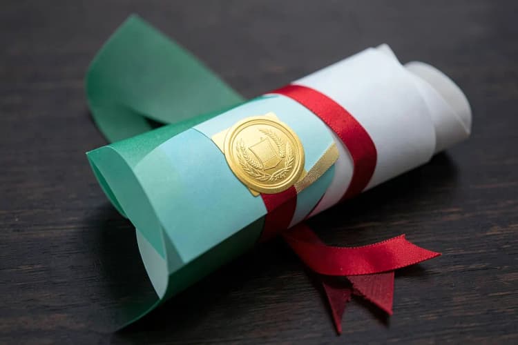 Um certificado com um selo dourado e uma fita vermelha, sobre uma superfície de madeira escura.